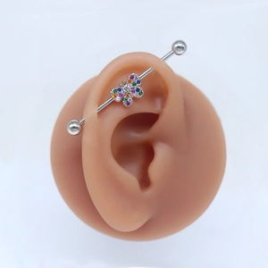 Detail view of silver industrial barbell earring featuring a colorful zircon butterfly