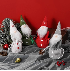 Close-up of four knitted Christmas gnomes gift bags with soft textures on red background