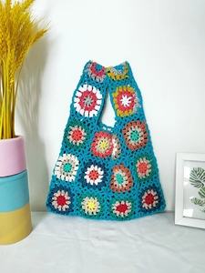 Close-up of handmade crochet bag detailing vibrant granny square patterns and peacock blue yarn