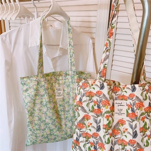 Detailansicht von zwei Blumen-Stofftaschen mit grünen und orangefarbenen Mustern in hellem Licht