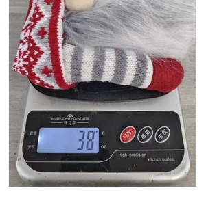 Détail d'un couvre-bouteille de vin gnome de Noël tricoté pesant 38g sur une balance.