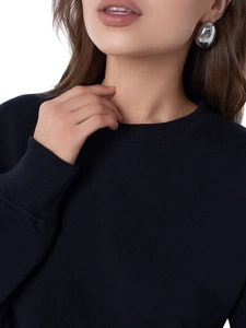 Close-up of black crewneck sweatshirt collar and a polished silver teardrop earring
