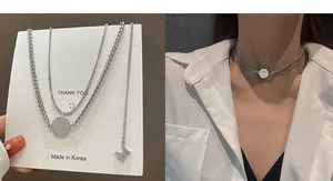 Close-up of layered silver hip-hop necklace with engraved MISS coin and M pendant charms