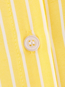 Macro shot of white resin button and fine yellow striped fabric on the shirt placket