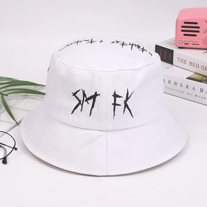 Detailed close-up of white bucket hat with black SMFK graffiti print and studio props