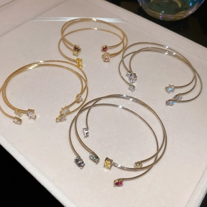 Detail of four double-layer open bangles with colorful zircon stones in a velvet box