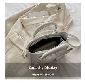 Interior view showing capacity of white bow handbag with long shoulder strap