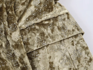 Detailed macro of gold velvet fabric with silver glitter floral rose pattern and soft sheen
