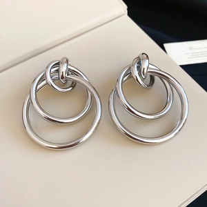Détail de boucles d'oreilles circulaires imbriquées argentées au fini métal poli