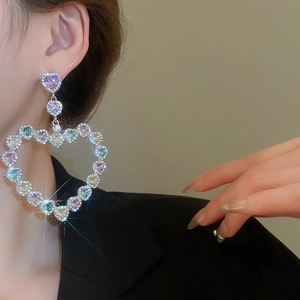 Gros plan de boucles d'oreilles cœur avec pierres colorées portées par un mannequin