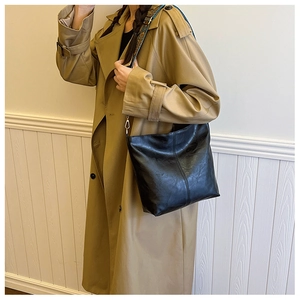 Detail of black soft PU leather handbag with wide vintage patterned shoulder strap