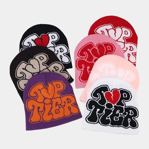 Macro shot of knitted beanies with TOP TIER jacquard lettering and heart patterns
