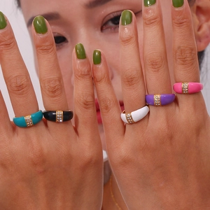 Model wearing gold-plated dome rings set with colorful enamel inlay and diamonds