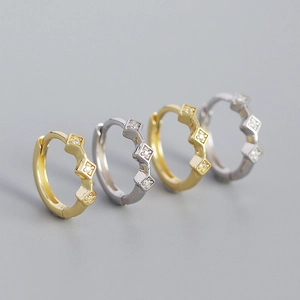 Macro shot of geometric diamond shaped earrings in gold and silver finish on gray background