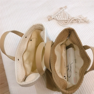 Detailed top view of beige and khaki woven tote bags with leather handles and zip closure