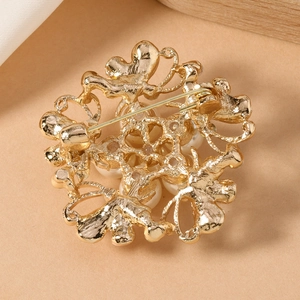 Macro detail of golden metal brooch back featuring premium white faux pearl and secure pin