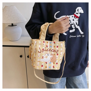 Detail of yellow canvas bucket bag with strawberry prints and adjustable shoulder strap