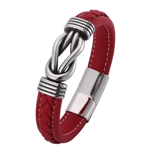 Detail of red braided leather bracelet with silver metal clasp and central knot pendant
