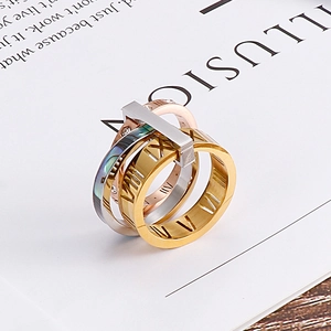 Detailed close-up of triple-tone titanium steel rings with shell inlays and Roman numerals