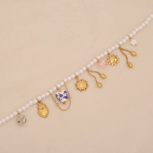 Close-up of baroque pearl bracelet with gold sun and heart charms on beige background