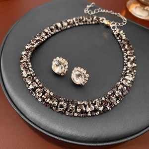 Close-up of sparkling square rhinestone necklace and stud earring set on black leather