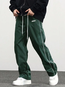 Detail of dark green jogger pants featuring white drawstrings and side stripe accents