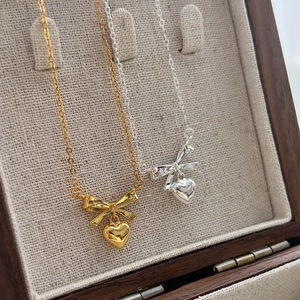 Elegant 925 sterling silver necklace with a golden bow and heart pendant on a chain