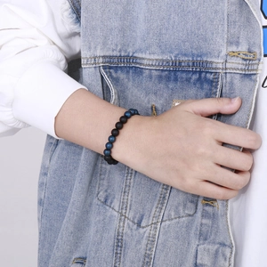 Close-up of 8mm matte black agate and blue beaded bracelet on a person's wrist
