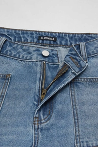 Gros plan de la taille d'un jean vintage bleu avec bouton argenté et détail de zip
