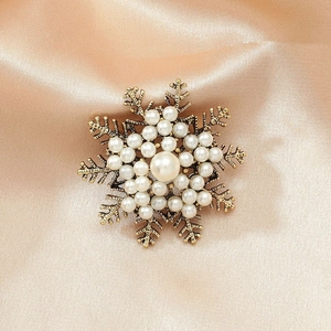 Détail macro de broche flocon de neige avec perles et fini or vieilli sur satin