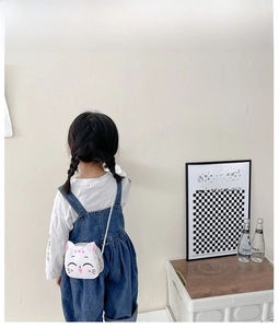 Rear view of a child wearing a cute white cartoon cat crossbody bag with blue denim dress