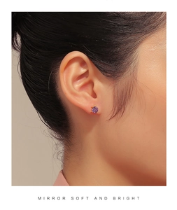Close-up of a woman wearing gold-plated turtle studs with purple cubic zirconia stones