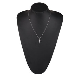 Close-up of a silver mirror-finish cross pendant necklace on a black mannequin bust