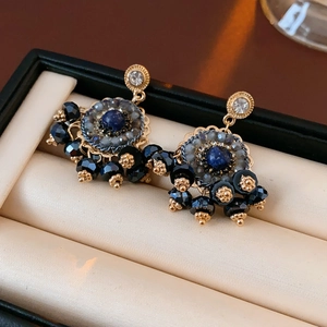 Dettaglio orecchini a fiore vintage con pietre blu e finiture in metallo dorato