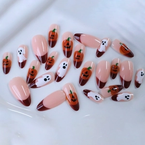 Faux ongles amande Halloween avec base nude, pointes rouges, motifs citrouille et fantôme
