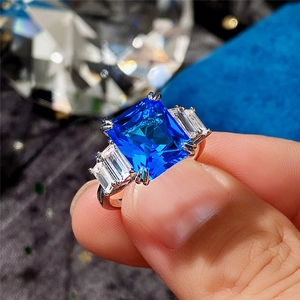 Macro detail of a square blue zircon ring with step-cut sapphire color and silver band