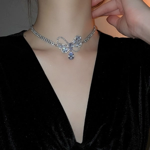 Silver bow necklace with teardrop zircon pendant worn on model with elegant black dress