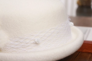 Detailed view of elegant white wool beret featuring retro mesh net and soft fur pompom