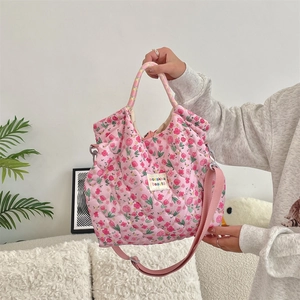 Detailed shot of pink quilted floral handbag with adjustable strap and designer label
