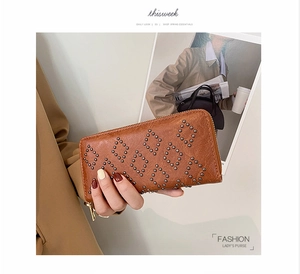 Details der karamellbraunen Clutch mit geometrischen Nieten und goldenem Reißverschluss