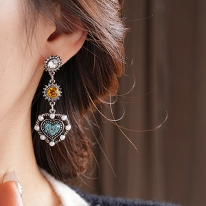 Detail of vintage heart earrings with blue crystals and pearls worn by a model