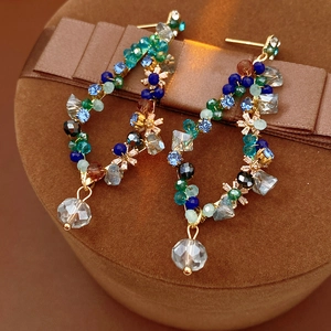 Macro shot of vintage gold wire earrings with colorful crystal beads and teardrop pendant