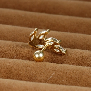 Macro view of gold leaf stud earring with clear zircon stones on a brown velvet stand