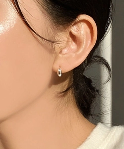 Close-up of minimalist polished silver oval hoop earring worn on ear for daily style