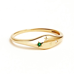 Detail of star-engraved gold ring with emerald and diamond zircon accents