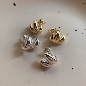 Macro shot of minimalist twisted double hoop earrings in gold and silver finish