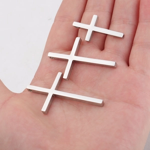 Set of three mirror polished stainless steel cross pendants in various sizes held by hand
