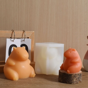 Detail view of 3D Capybara silicone mold with finished candles on a natural wooden desk