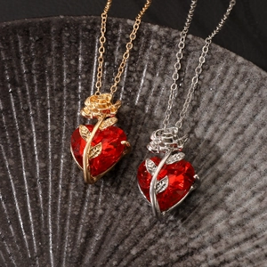 Gothic rose heart necklaces in gold and silver finish on a dark ceramic plate