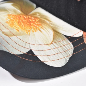 Close-up of black baseball cap brim with floral embroidery and orange stitching